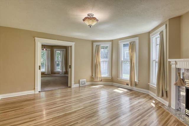 1428 E 18th Ave, Spokane, WA 99203 - unfurnished living room with light wood finished floors, a fireplace, and a textured ceiling