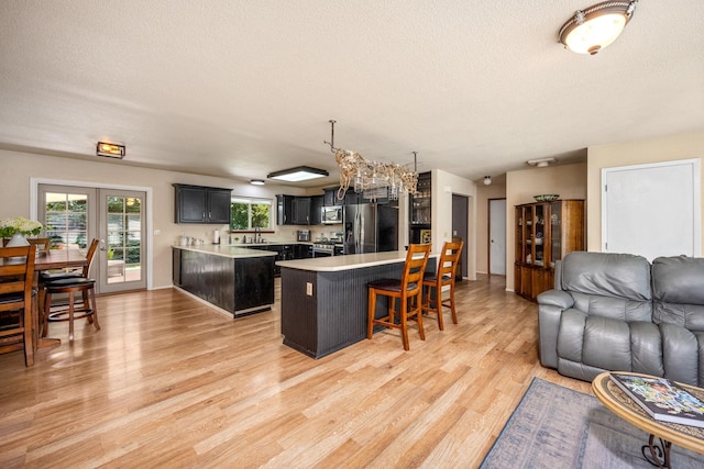 447 E Dakota Ave, Hayden, ID 83835 - kitchen featuring open floor plan, stainless steel appliances, a kitchen breakfast bar, light countertops, and a textured ceiling