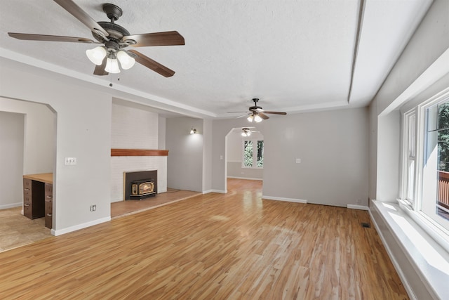 17221 N Little Spokane Dr, Colbert, WA 99005 - unfurnished living room featuring a ceiling fan, light wood-style flooring, a wood stove, and arched walkways