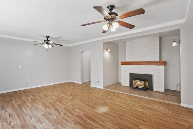 17221 N Little Spokane Dr, Colbert, WA 99005 - unfurnished living room with a ceiling fan, light wood-type flooring, a wood stove, and arched walkways