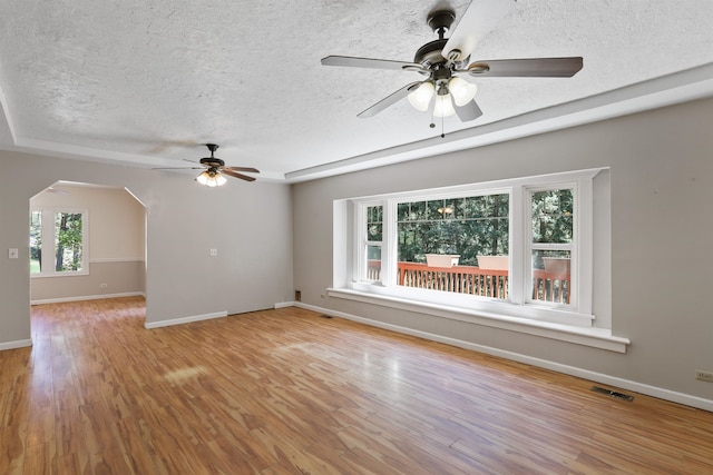17221 N Little Spokane Dr, Colbert, WA 99005 - empty room featuring ceiling fan, a textured ceiling, arched walkways, and wood finished floors