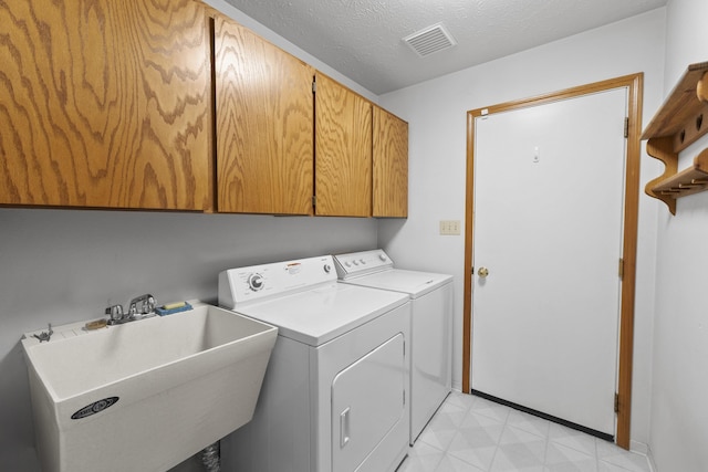 17607 E Judkins Rd, Spokane, WA 99217 - laundry area featuring cabinet space, washing machine and clothes dryer, a textured ceiling, and light floors