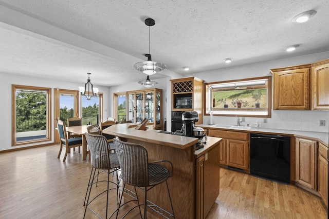 17607 E Judkins Rd, Spokane, WA 99217 - kitchen with black appliances, a textured ceiling, a kitchen breakfast bar, light wood-style floors, and a kitchen island