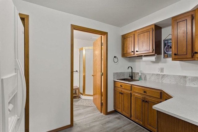 996A Basin Rd, Colville, WA 99114 - kitchen with light countertops, light wood-type flooring, brown cabinets, and freestanding refrigerator