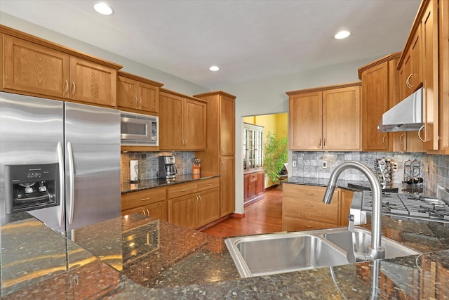 2716 S Man O War Ln, Veradale, WA 99037 - kitchen with appliances with stainless steel finishes, brown cabinetry, tasteful backsplash, wall chimney range hood, and recessed lighting