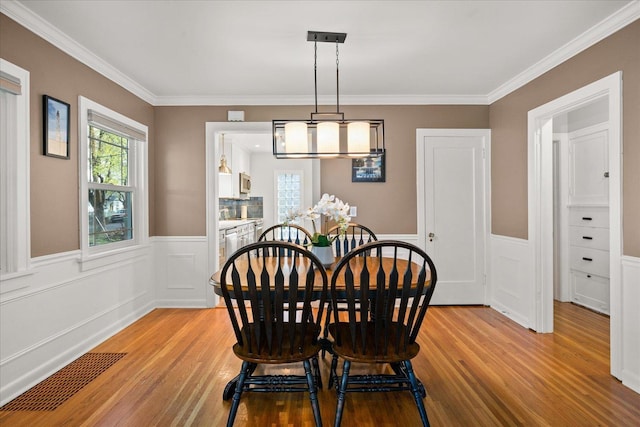 1123 W 25th Ave, Spokane, WA 99203 - dining area featuring light wood finished floors, healthy amount of natural light, a wainscoted wall, and crown molding