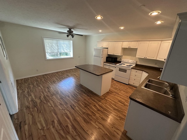 360 E 7th Ave # B, Colville, WA 99114 - kitchen with white appliances, dark countertops, a center island, dark wood finished floors, and recessed lighting
