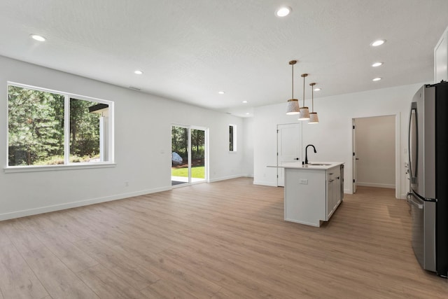 1215 S Radio Ln, Spokane Valley, WA 99212 - kitchen with freestanding refrigerator, light wood finished floors, recessed lighting, light countertops, and an island with sink