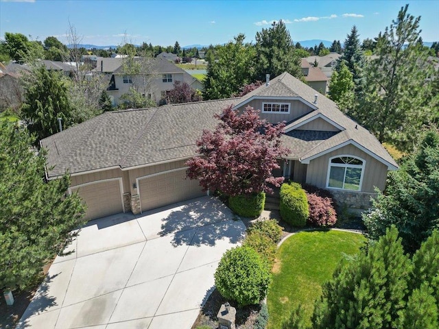 3405 W Kens Ct, Spokane, WA 99208 - view of front of home with stone siding, an attached garage, concrete driveway, roof with shingles, and a residential view