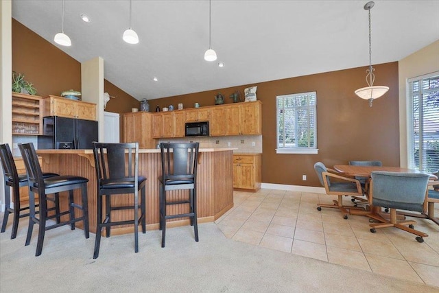 3405 W Kens Ct, Spokane, WA 99208 - kitchen with black appliances, a kitchen bar, hanging light fixtures, light colored carpet, and light tile patterned floors