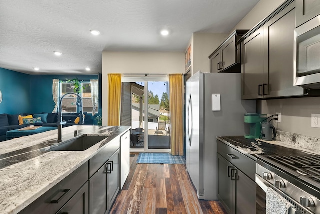 3228 N Mckinnon Rd, Spokane, WA 99217 - kitchen featuring stainless steel appliances, open floor plan, dark wood-style flooring, light stone counters, and a textured ceiling