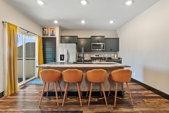 3228 N Mckinnon Rd, Spokane, WA 99217 - kitchen featuring stainless steel appliances, a kitchen island with sink, recessed lighting, a kitchen bar, and dark wood-style floors