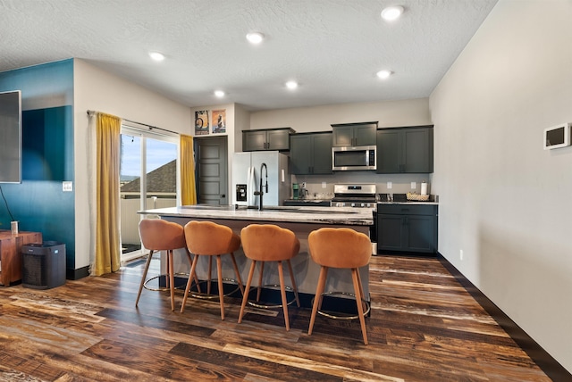 3228 N Mckinnon Rd, Spokane, WA 99217 - kitchen featuring stainless steel appliances, a kitchen bar, a kitchen island with sink, dark wood-style floors, and recessed lighting