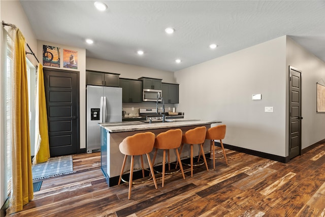 3228 N Mckinnon Rd, Spokane, WA 99217 - kitchen with appliances with stainless steel finishes, an island with sink, dark wood-style floors, a breakfast bar, and recessed lighting