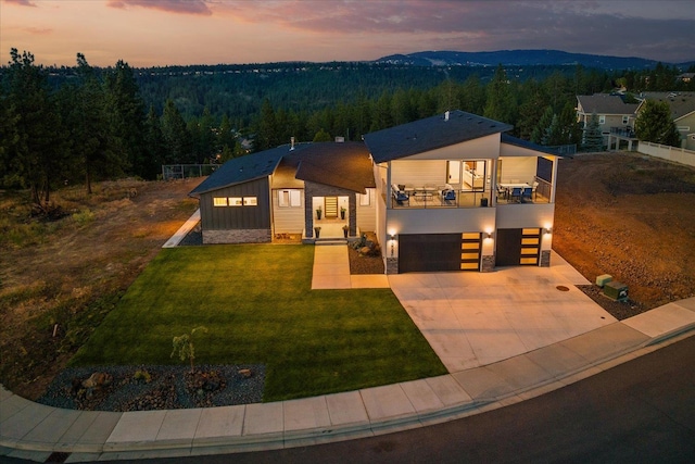 5257 S Falcon Point Ct, Spokane, WA 99224 - contemporary house with a balcony, a view of trees, a garage, a lawn, and board and batten siding