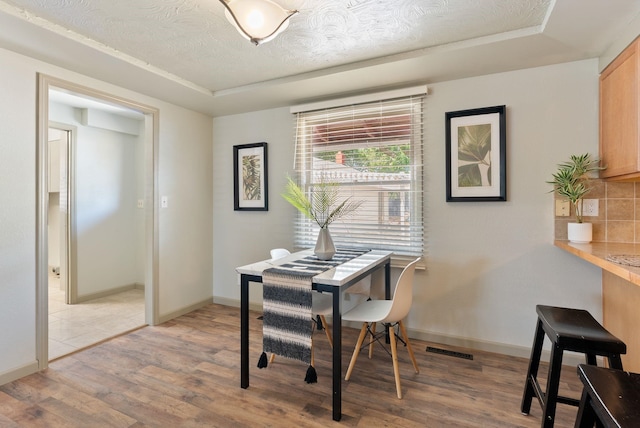 12911 E Desmet Ave, Spokane, WA 99216 - dining room with light wood-type flooring, a tray ceiling, a desk, and a textured ceiling