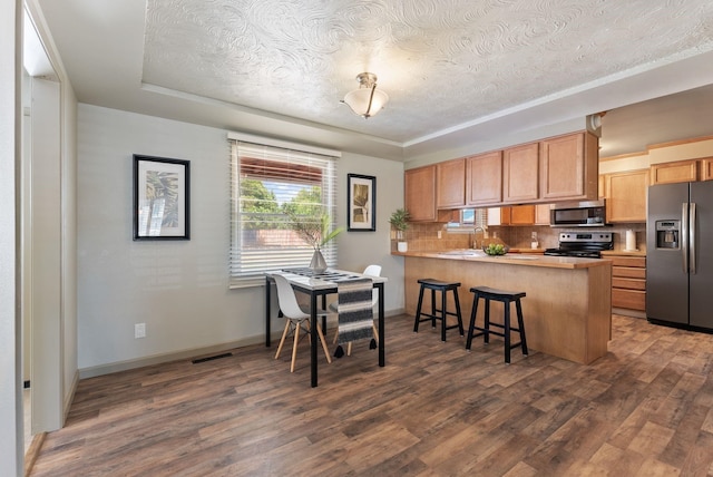 12911 E Desmet Ave, Spokane, WA 99216 - kitchen featuring stainless steel appliances, a textured ceiling, a peninsula, tasteful backsplash, and dark wood-type flooring