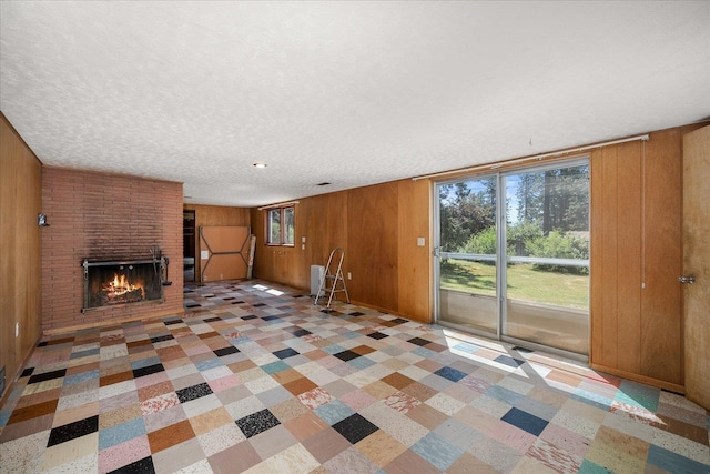 11322 E 18th Ave, Spokane, WA 99206 - unfurnished living room with wood walls, a brick fireplace, and a textured ceiling