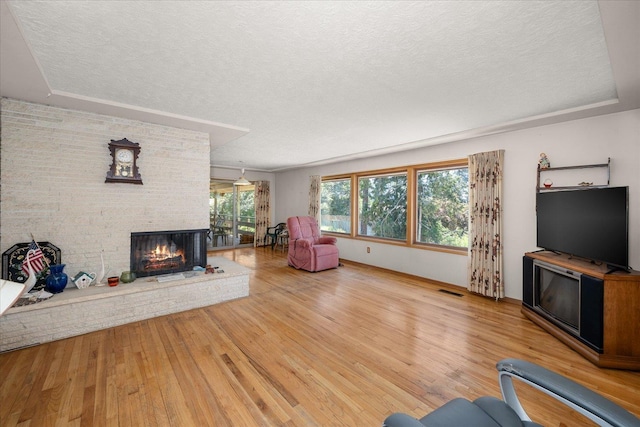 11322 E 18th Ave, Spokane, WA 99206 - living area with a textured ceiling, wood finished floors, and a brick fireplace