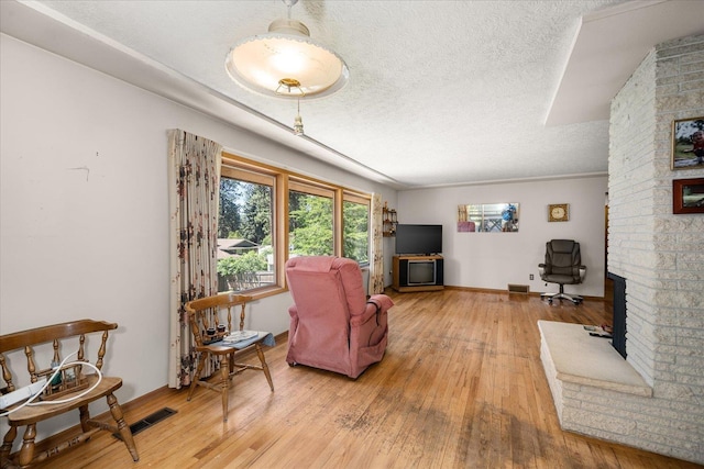 11322 E 18th Ave, Spokane, WA 99206 - living room featuring a textured ceiling, light wood-style floors, and a fireplace