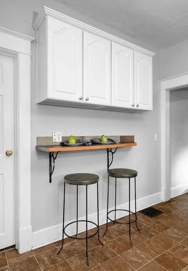 1518 W 6th Ave, Spokane, WA 99204 - kitchen with a breakfast bar, white cabinets, and stone finish flooring