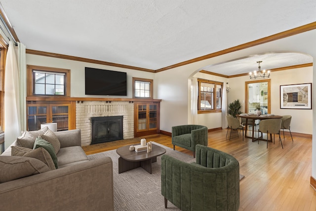 19 E 28th Ave, Spokane, WA 99203 - living area with arched walkways, a chandelier, a brick fireplace, light wood finished floors, and crown molding