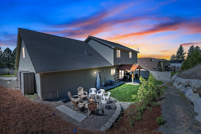 16319 E Whirlaway Ln, Veradale, WA 99037 - back of property at dusk featuring a fire pit, a patio, a fenced backyard, and a shingled roof