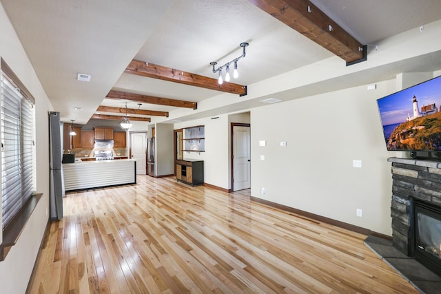 16319 E Whirlaway Ln, Veradale, WA 99037 - unfurnished living room featuring light wood-type flooring, beam ceiling, and a fireplace