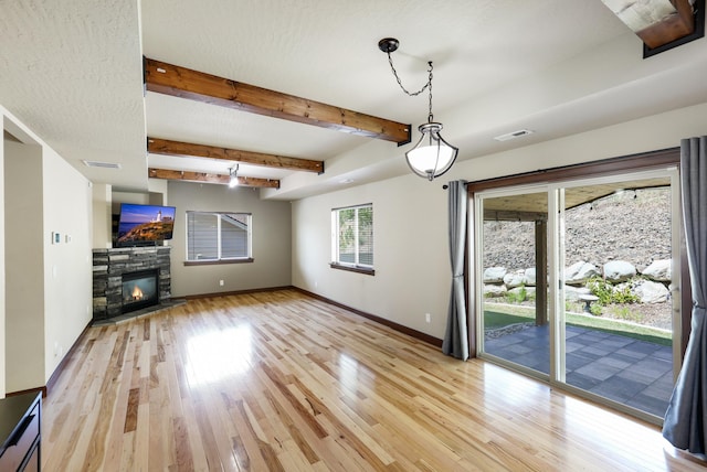 16319 E Whirlaway Ln, Veradale, WA 99037 - unfurnished living room with light wood-style flooring, a fireplace, and beamed ceiling
