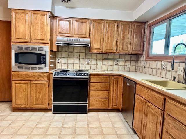 6412 N Fotheringham St, Spokane, WA 99208 - kitchen with stainless steel appliances, under cabinet range hood, light countertops, and backsplash