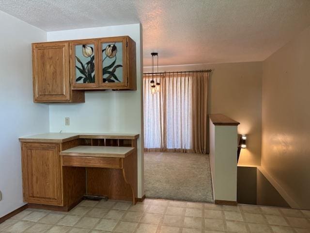 6412 N Fotheringham St, Spokane, WA 99208 - kitchen featuring a textured ceiling, brown cabinets, light flooring, and glass insert cabinets