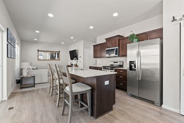 1225 E Paske Rd, Colbert, WA 99005 - kitchen featuring stainless steel appliances, light wood finished floors, a kitchen bar, a center island with sink, and dark brown cabinets