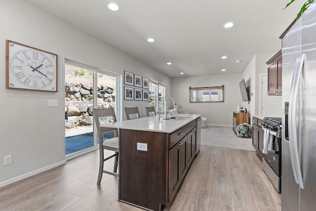1225 E Paske Rd, Colbert, WA 99005 - kitchen with appliances with stainless steel finishes, light wood-style floors, a center island with sink, dark brown cabinets, and recessed lighting