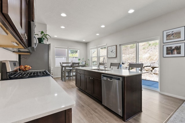 1225 E Paske Rd, Colbert, WA 99005 - kitchen with stainless steel appliances, light countertops, dark brown cabinets, light wood-style floors, and a kitchen island with sink