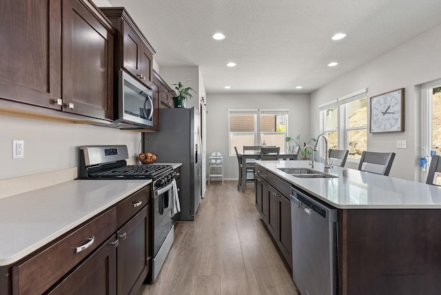 1225 E Paske Rd, Colbert, WA 99005 - kitchen with appliances with stainless steel finishes, an island with sink, light wood-style flooring, light countertops, and dark brown cabinets