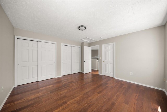 4407 E 14th Ave, Spokane, WA 99212 - unfurnished bedroom with dark wood-style flooring, two closets, attic access, and a textured ceiling