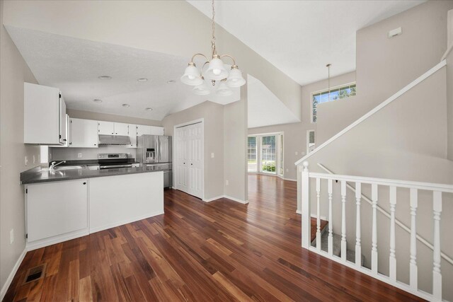 4407 E 14th Ave, Spokane, WA 99212 - kitchen with stainless steel appliances, dark countertops, dark wood-style floors, under cabinet range hood, and a chandelier