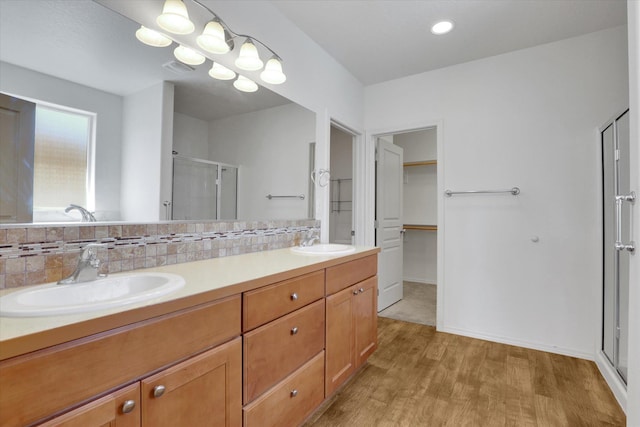 8812 W Pirates Ct, Spokane, WA 99224 - full bath with a stall shower, wood finished floors, double vanity, a spacious closet, and backsplash