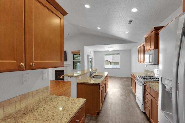 8812 W Pirates Ct, Spokane, WA 99224 - kitchen with refrigerator with ice dispenser, white range with gas cooktop, vaulted ceiling, a lit fireplace, and backsplash
