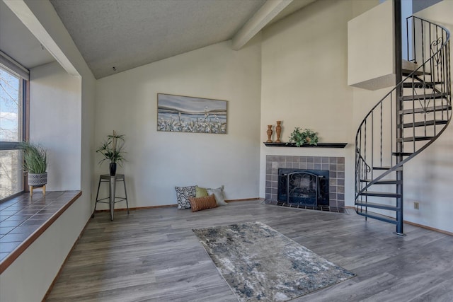 707 W 6th Ave Unit 44, Spokane, WA 99204 - living area featuring wood finished floors, a tile fireplace, stairs, and high vaulted ceiling