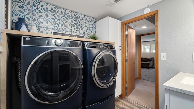 811 W Teal Ave, Spokane, WA 99218 - washroom with washer and dryer, cabinet space, light wood-type flooring, and light carpet