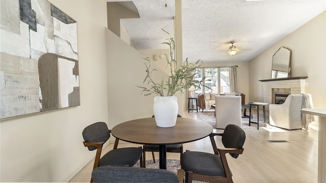 5623 W Lyons Ct, Spokane, WA 99208 - dining space with a ceiling fan, a brick fireplace, wood finished floors, and a textured ceiling