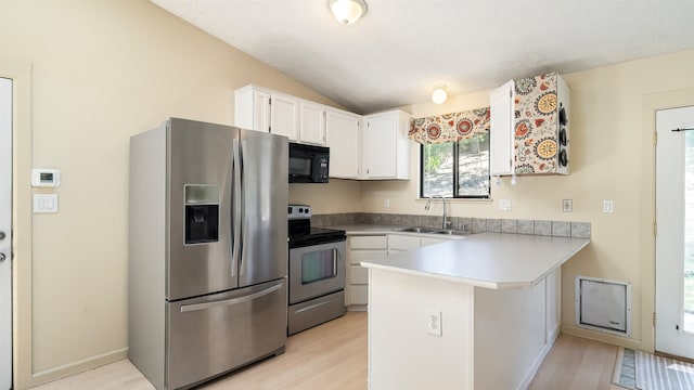 5623 W Lyons Ct, Spokane, WA 99208 - kitchen with stainless steel appliances, a peninsula, vaulted ceiling, white cabinetry, and light wood-style floors