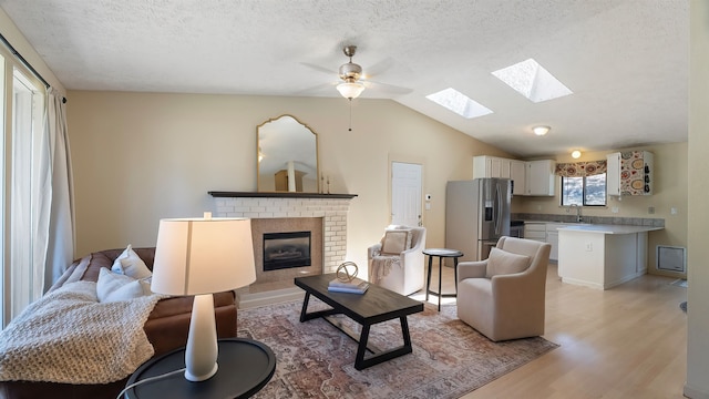 5623 W Lyons Ct, Spokane, WA 99208 - living area featuring a skylight, light wood-style floors, ceiling fan, a textured ceiling, and a fireplace