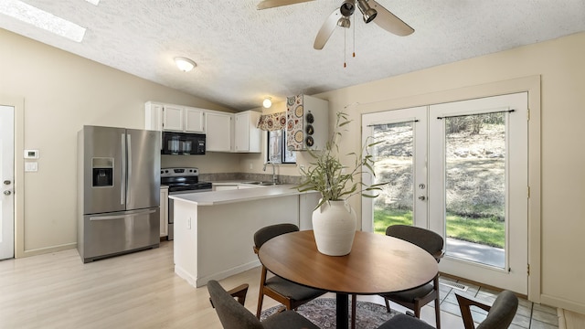 5623 W Lyons Ct, Spokane, WA 99208 - kitchen with stainless steel appliances, healthy amount of natural light, a textured ceiling, vaulted ceiling, and white cabinetry
