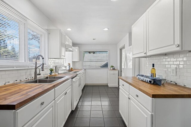 3129 E 34th Ave, Spokane, WA 99223 - kitchen with wood counters, backsplash, dark tile patterned floors, white range with electric cooktop, and white cabinetry