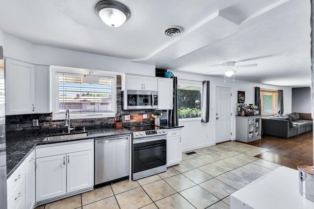 5917 N Addison St, Spokane, WA 99208 - kitchen with stainless steel appliances, tasteful backsplash, light tile patterned flooring, white cabinets, and a ceiling fan