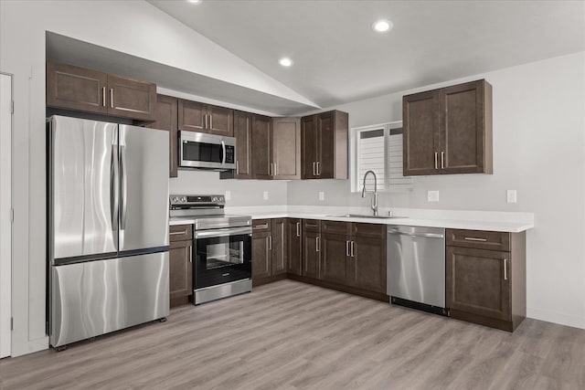 2912 E Wabash Ave, Spokane, WA 99217 - kitchen with stainless steel appliances, lofted ceiling, dark brown cabinets, light wood finished floors, and light countertops