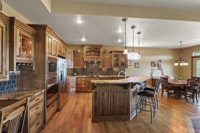 1604 N Rim View St, Spokane, WA 99224 - kitchen with stainless steel appliances, light wood-style floors, decorative backsplash, glass insert cabinets, and brown cabinets