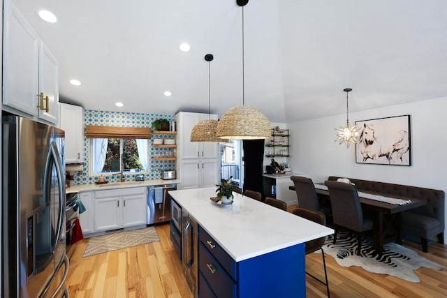 18017 N Lidgerwood Ct, Colbert, WA 99005 - kitchen with freestanding refrigerator, dishwasher, light wood finished floors, a kitchen bar, and light countertops